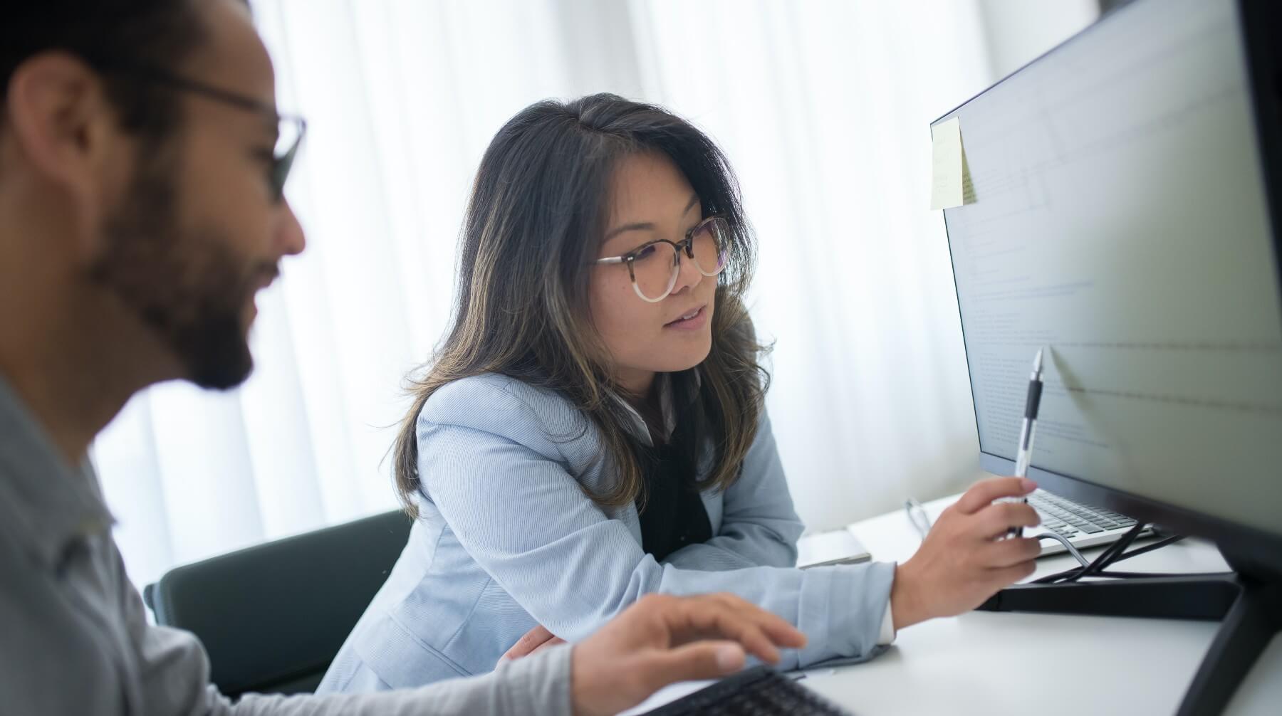 Coworkers laugh while working on their laptops