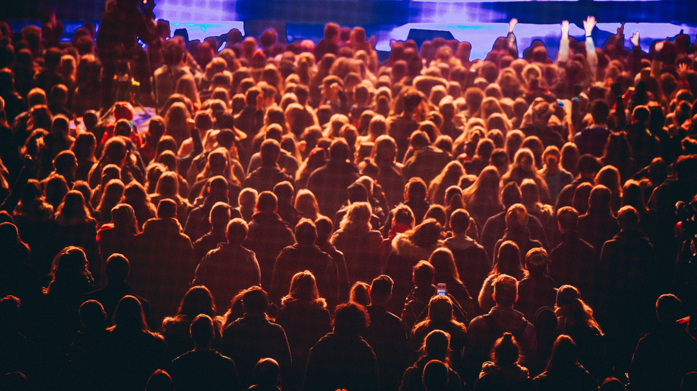 the backs of a large crowd looking towards a stage