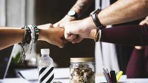 Team fist pumping in an office environment