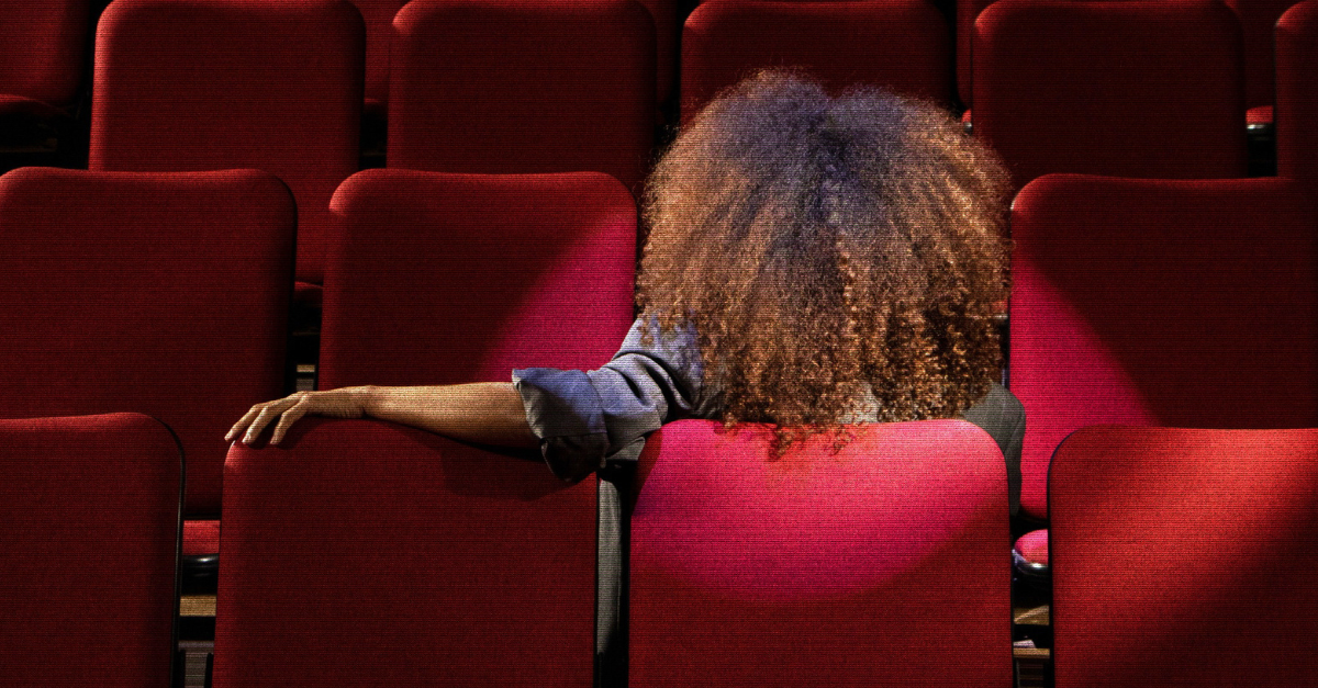 Lady sat backwards in a row of red theatre seats