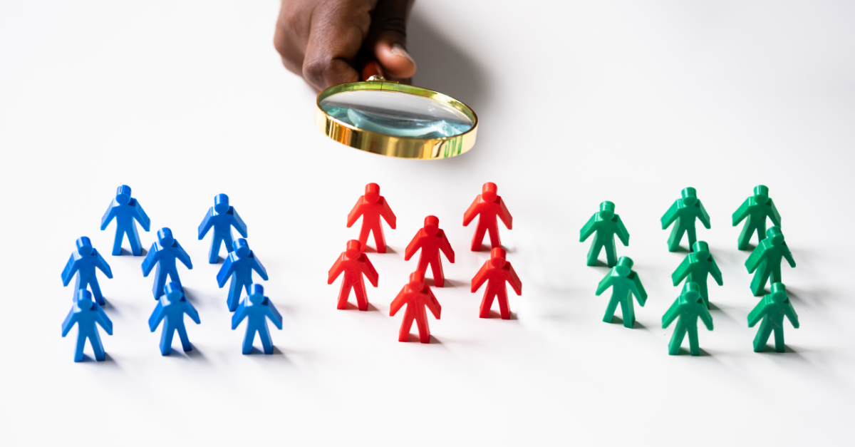 Magnifying glass above three groups of stick figures - blue, red and green.